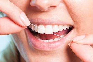 A woman Flossing her Teeth and Gums