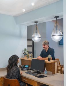 Reception area at Surf City Dental with staff assisting a patient, featuring modern decor and calming atmosphere, aligning with sedation dentistry services.
