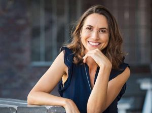 Smiling woman resting her chin on her hand, showcasing confidence and comfort, reflecting the relaxing atmosphere of Surf City Dental's sedation dentistry services.