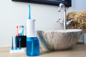 Water flosser with interchangeable tips on a bathroom countertop, showcasing effective dental hygiene tools for improved oral health resolutions.